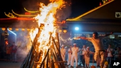 A man sets wood on fire to prepare for worshipers to walk barefoot over burning coals during the Nine Emperor Gods festival at a temple in Kuala Lumpur, Malaysia.