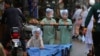 Boys cover their faces with plastic bags while pushing a handcart during rainfall in Peshawar, Pakistan.