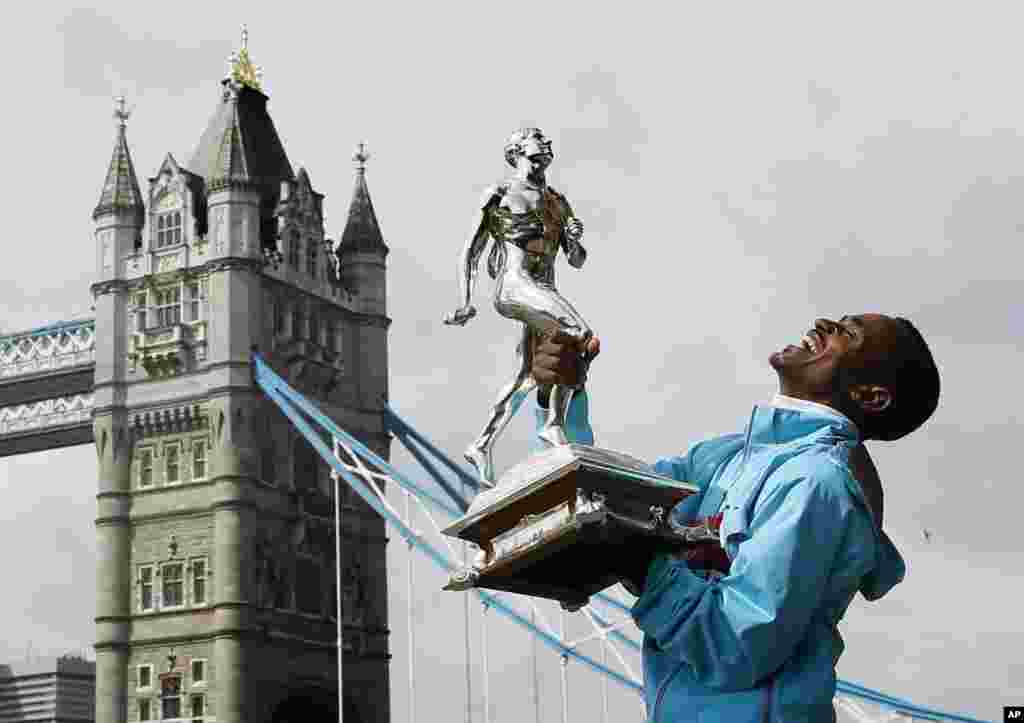 The winner of the men&#39;s 2013 London Marathon, Tsegaye Kebede of Ethiopia, laughs as he holds the trophy at a photo call by Tower Bridge in London.