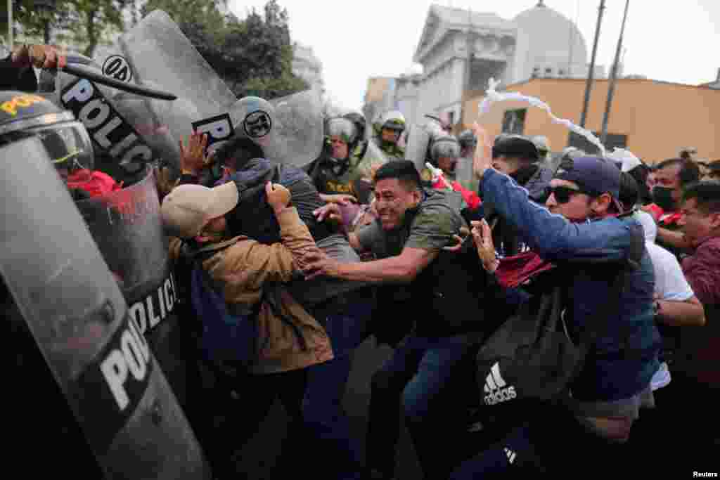 Manifestantes confrontam a polícia de choque durante um protesto exigindo eleições presidenciais e o encerramento do Congresso após o líder peruano deposto Pedro Castillo ter sido detido numa prisão policial após a sua destituição, em Lima, a 8 de Dezembro de 2022.