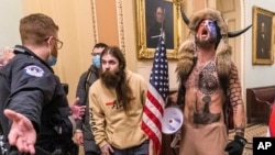 FILE - In this Jan. 6, 2021 file photo, supporters of Donald Trump, including Jacob Chansley, right with fur hat, are confronted by U.S. Capitol Police officers outside the Senate Chamber inside the Capitol in Washington. 