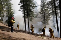 FILE - Firefighters hold the line along a containment area while fighting the King fire in Mosquito, Calif., Sept. 23, 2014.