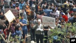 A demonstrator holds a burning placard with a picture of Syria's President Bashar al-Assad after Friday prayers in Talbiseh, near Homs, April 20, 2012. The sign on the right reads 'No to medicines; yes to freedom.'