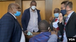 Journalist Hopewell Chin’ono, 2nd from left, talks to his lawyers Nov. 12, 2020, after Magistrate Marehwanazvo Gofa denied him bail on grounds that he had high propensity to abuse social media again. (Columbus Mavhunga/VOA)