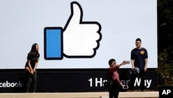 FILE - Visitors take photos in front of the Facebook logo at the company's headquarters, March 28, 2018, in Menlo Park, Calif.