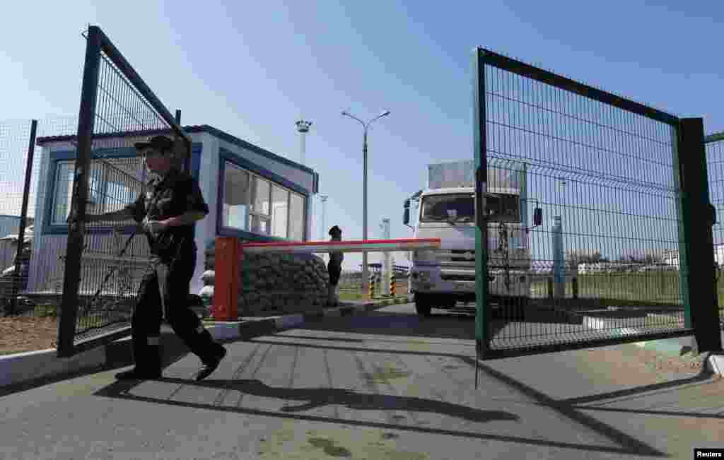 A Russian border guard opens a gate in front of a truck from a convoy that delivered humanitarian aid for Ukraine on its return to Russia at border crossing point "Donetsk" in Russia's Rostov Region, Aug. 23, 2014. 