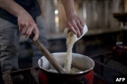 FILE - Mapuche indigenous Ricardo Melinir cooks with pinon — fruit of the araucaria tree — flour as he prepares Mapuche traditional dishes for tourists in Quinquen, Temuco, Chile, Oct. 24, 2018.