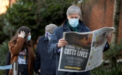 A man reads a newspaper as he waits to enter Lord's Cricket Ground to receive the coronavirus vaccine, in London, Britain, Jan. 22, 2021.