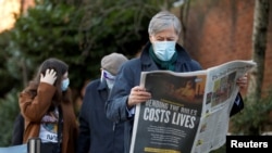 A man reads a newspaper as he waits to enter Lord's Cricket Ground to receive the coronavirus vaccine, in London, Britain, Jan. 22, 2021. 
