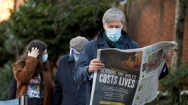 A man reads a newspaper as he waits to enter Lord's Cricket Ground to receive the coronavirus vaccine, in London, Britain, Jan. 22, 2021.