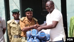 Pastor Yohanna Buru, founder of the Peace, Revival and Reconciliation Foundation, hands the organization's donation to a prison officer at Kaduna Central Prison.