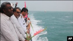 ژماره‌یه‌ک له‌ که‌سوکاری قوربانیانی فڕۆکه‌که‌ به‌ گوڵه‌وه‌ چوونه‌ته‌ شـوێنی که‌وتنی فڕۆکه‌که‌ له‌ که‌نداو، شه‌ممه‌ 3 ی حه‌وتی 2010