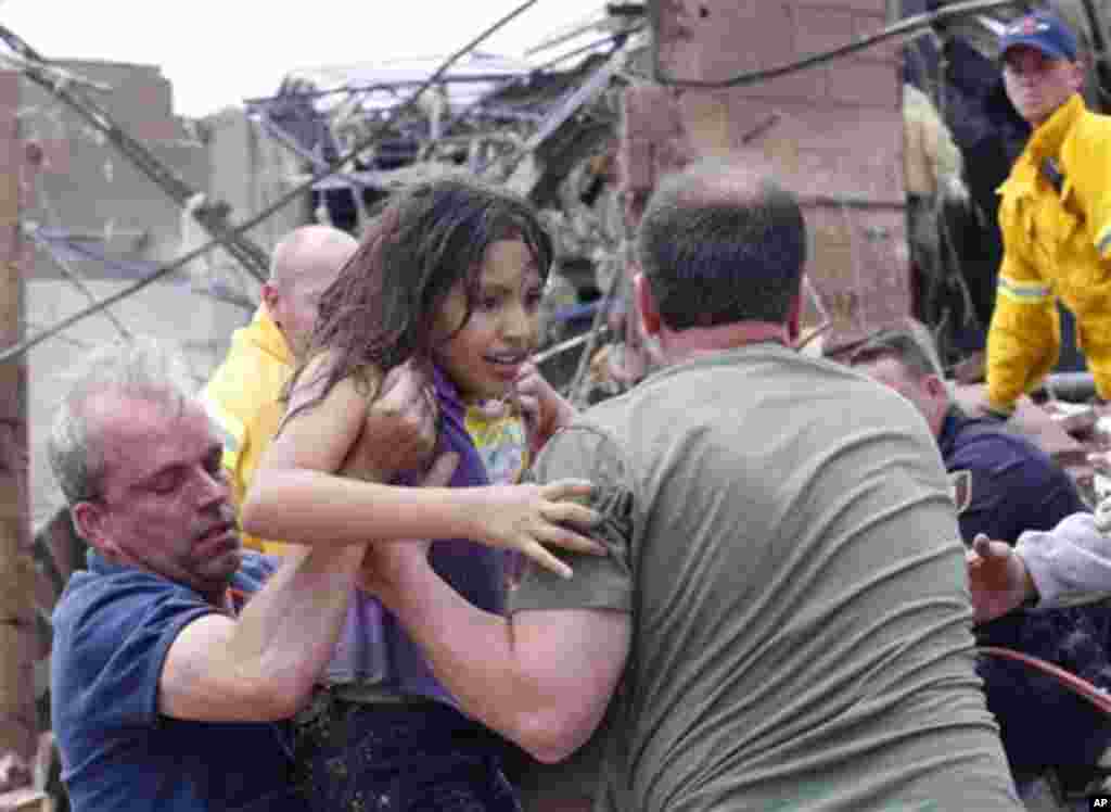 A child is pulled from the rubble of the Plaza Towers Elementary School in Moore, Okla., and passed along to rescuers Monday, May 20, 2013. 