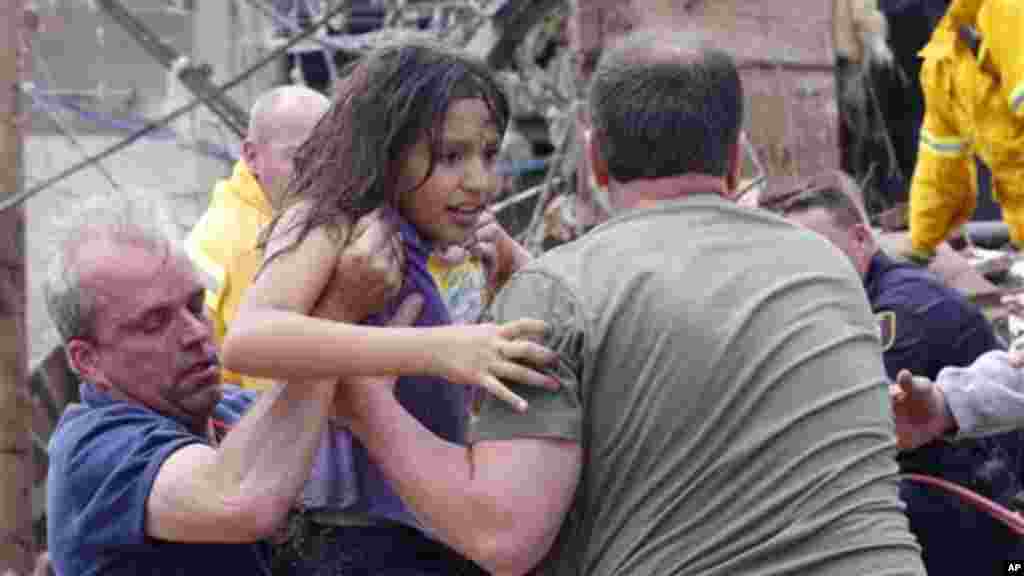 A child is pulled from the rubble of the Plaza Towers Elementary School in Moore, Okla., and passed along to rescuers Monday, May 20, 2013.