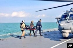 FILE - Royal Malaysian Navy personnel carry a body onto a U.S. Navy helicopter from USS America during a search and rescue operation for survivors of the USS John S. McCain.