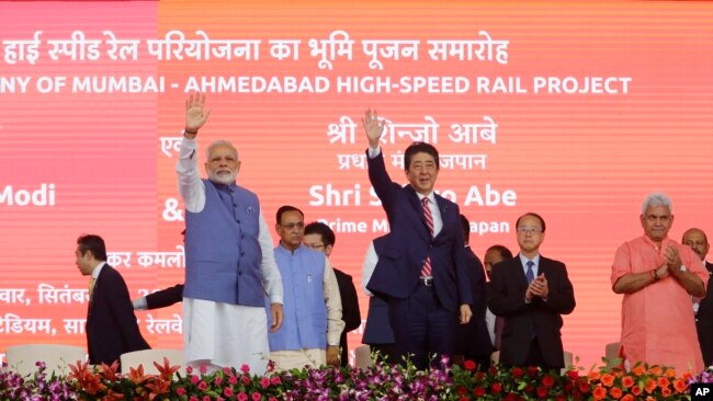 Japanese Prime Minister Shinzo Abe, right and Indian Prime Minister Narendra Modi wave during the ground breaking ceremony for high speed rail project in Ahmadabad, India, Sept. 14, 2017. 