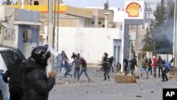 Protesters throw items at police forces in the city of Ennour, near Kasserine, Tunisia, Jan. 20, 2016. Tunisia has declared a curfew in the western city after clashes between police and more than 1,000 young protesters demonstrating for jobs. 
