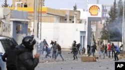 Demonstran melempari polisi di kota Ennour, dekat Kasserine, Tunisia, Rabu, 20 Januari 2016. Tunisia menerapkan jam malam di kota sebelah barat itu setelah bentrokan berlangsung antara polisi dan lebih dari 1.000 demonstran pemuda yang menuntut pekerjaan.