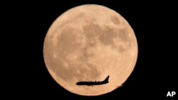 Un avion vole au travers la lune à Beijing, Chine, le 14 novembre 2016.