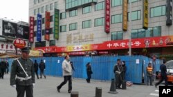 Chinese guards stand at the entrance of the pedestrian Wangfujing area in Beijing. In the background are the blue metal barriers of a construction site that partially blocks the designated spot for anti-government protests, February 25, 2011.