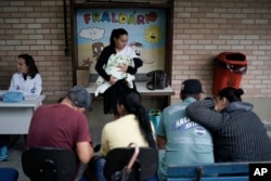 Una madre sostiene a su bebé después de recibir una vacuna contra la poliomielitis en Río de Janeiro, Brasil, el lunes 6 de agosto de 2018. Las autoridades sanitarias brasileñas lanzaron una campaña de vacunación nacional contra el sarampión y la poliomielitis, dos enfermedades que aparecen en mayor cantidad en la nación más grande de América Latina después de haber sido casi erradicadas. (AP Photo / Leo Correa).