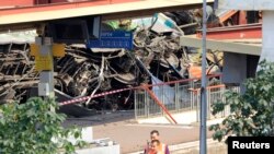 French railway officials stand next to the wreckage of a derailed train at the Bretigny-sur-Orge station near Paris July 13, 2013.