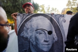 A union worker holds a banner during a protest against NAFTA negotiations outside the site of the fifth round of talks involving the United States, Mexico and Canada in Mexico City, Nov. 17, 2017.