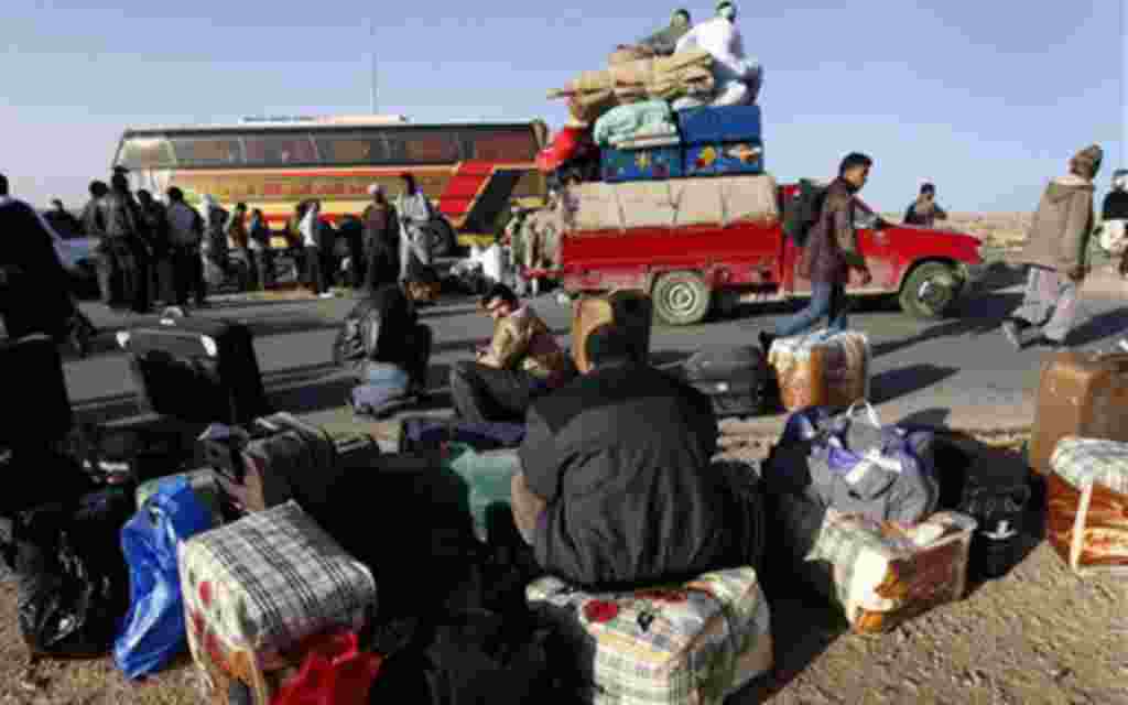 Egyptians who fled from Libya through the Salloum land port gate wait with their belongings at the Egyptian-Libyan border, in Salloum, Egypt, Tuesday, Feb. 22, 2011. An estimated 5,000 Egyptians have returned home from Libya by land, and about 10,000 more