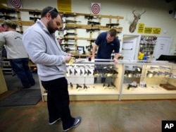 FILE - David Foley, center, looks as a handgun while shopping at the Spring Guns and Ammo store, Jan. 4, 2016, in Spring, Texas.
