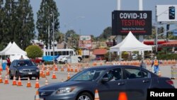 FILE - A person drives through a coronavirus testing center in Inglewood, California, July 20, 2020.