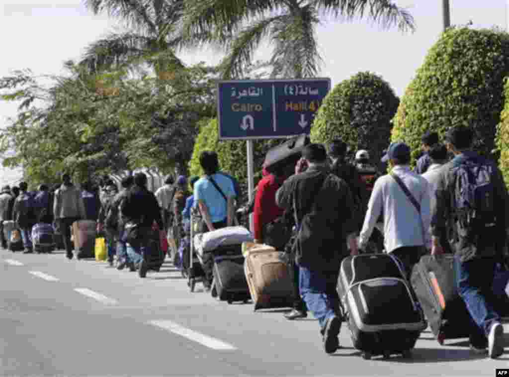 Tourists make their way to a terminal to attempt to leave Egypt, at Cairo airport, Egypt, Wednesday, Feb.2, 2011. The U.S. began evacuating nonessential government personnel and their families Wednesday, while crowds piled up at Cairo's airport as more th