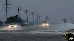 Vehicles navigate a flooded Highway 64 as wind pushes water over the road as Hurricane Arthur passes through Nags Head, N.C., July 4, 2014.