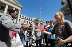 Patricia Ice, an attorney with the Mississippi Immigrants Rights Alliance, left, hands out flyers to Jordan Sanders of Vicksburg that call for the freeing of 22-year-old Daniela Vargas, an Argentine native who has lived in the United States since she was 7 years old, following a brief rally on her behalf at the Capitol in Jackson, Mississippi, March 3, 2017.