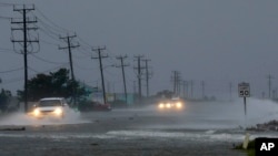 Kendaraan menembus banjir akibat angin Badai Arthur yang mendorong air ke jalanan di Nags Head, North Carolina (4/7).