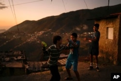 FILE - Children play with water during pre-carnival celebrations in the Catia neighborhood of Caracas, Venezuela, Friday, Feb. 17, 2023. (AP Photo/Matias Delacroix)