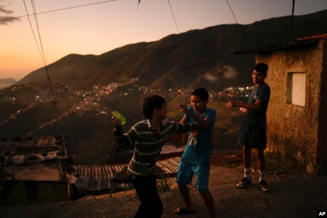 FILE - Children play with water during pre-carnival celebrations in the Catia neighborhood of Caracas, Venezuela, Friday, Feb. 17, 2023. (AP Photo/Matias Delacroix)