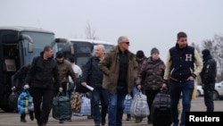 Men get off buses before reuniting with servicemen and officials of the self-proclaimed republics during the exchange of prisoners of war between Ukraine and the separatist republics near the Mayorsk crossing point in Donetsk region, Dec. 29, 2019.