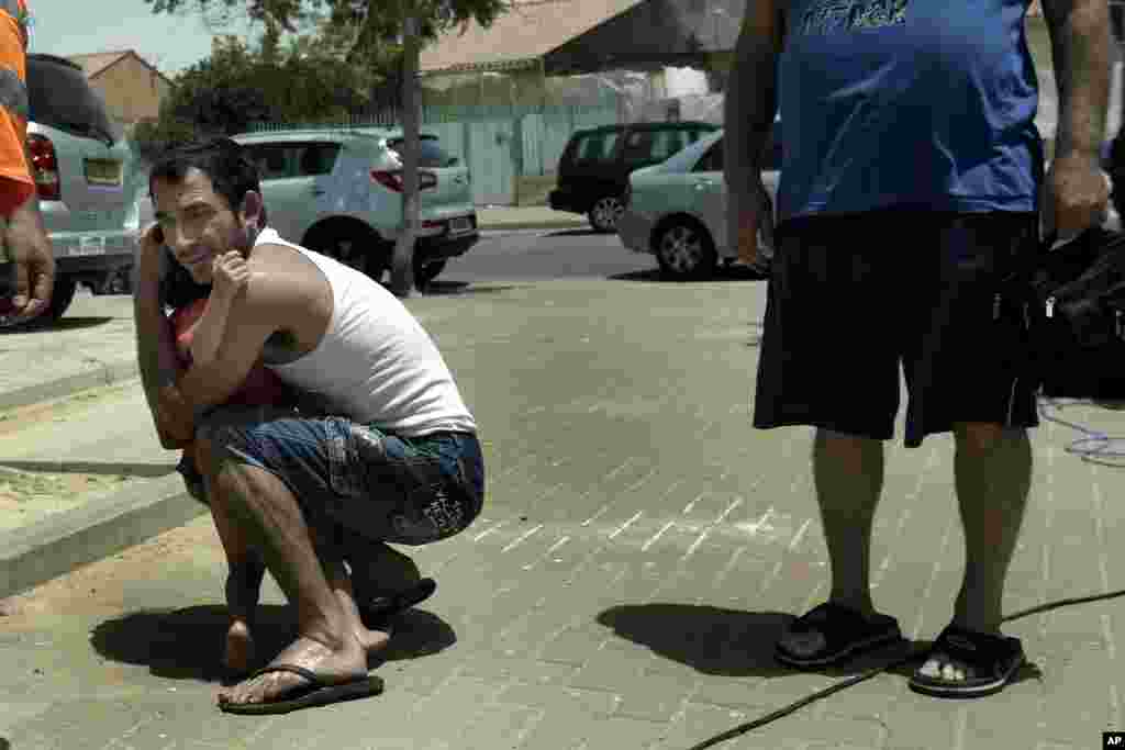 An Israeli hugs his child outside a shelter as a siren warning of incoming rockets is heard around the southern city of Beersheba, Israel, July 12, 2014. 