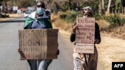 A man and a woman hold placards during an anti-corruption protest march along Borrowdale road, on July 31, 2020 in Harare.