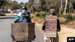A man and a woman hold placards during an anti-corruption protest march along Borrowdale road, on July 31, 2020 in Harare.