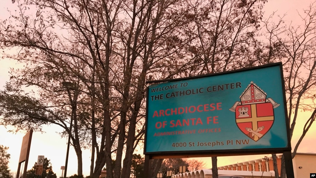 FILE - The sun sets on a sign in front of the Archdiocese of Santa Fe offices in Albuquerque, N.M., Nov. 29, 2018. A former Roman Catholic priest found guilty of sexual abuse in New Mexico and was sentenced Sept. 13, 2019, to 30 years in prison.