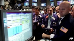 Specialist Jay Woods, right, works with traders on the floor of the New York Stock Exchange, June 28, 2012. 
