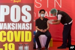 Seorang petugas kesehatan menerima suntikan vaksin Covid-19 di sebuah rumah sakit di Bali, pada Kamis, 14 Januari 2021. (Foto: AP)