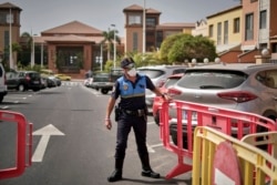 A Spanish police officer sets a barrier blocking the access to the H10 Costa Adeje Palace hotel in Tenerife, Canary Island, Spain, Feb. 25, 2020.