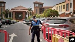 A Spanish police officer sets a barrier blocking the access to the H10 Costa Adeje Palace hotel in Tenerife, Canary Island, Spain, Feb. 25, 2020. 