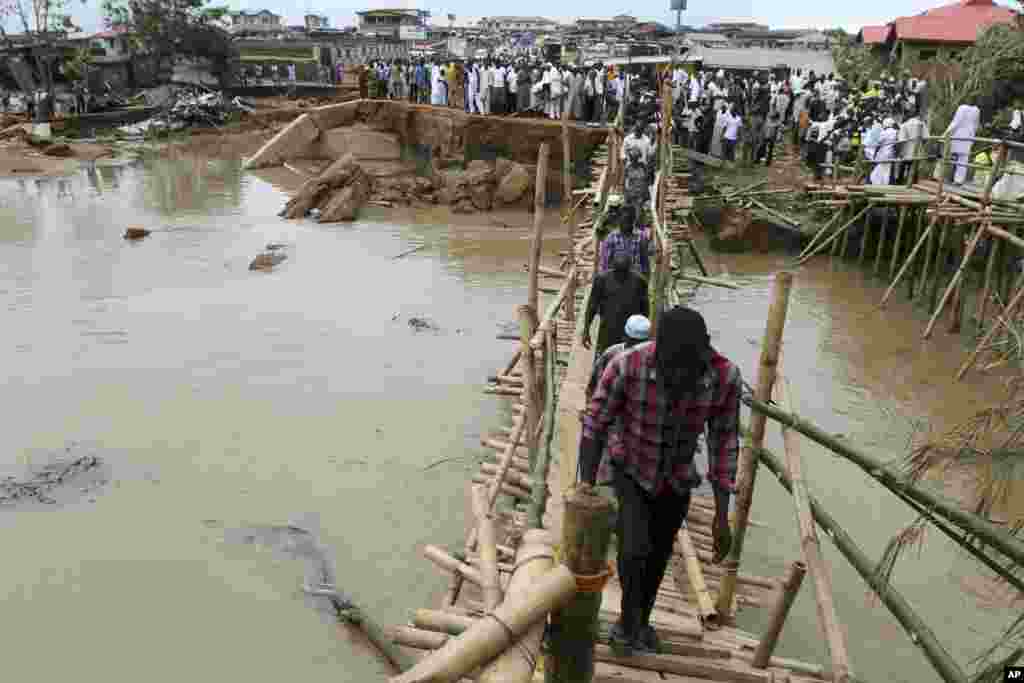 People queue to pass through a make-shift bridge after an heavy flood swept away a connecting bridge in Nigeria's south-west city of Ibadan.