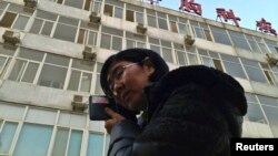FILE - Wang Yu, the lawyer of human right activist Cao Shunli, talks on the phone in front of a hospital building where Cao was hospitalized at its intensive care unit in Beijing, March 1, 2014.