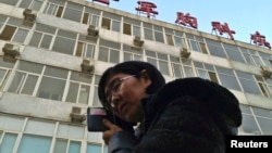 Wang Yu, the lawyer of human right activist Cao Shunli, talks on the phone in front of a hospital building where Cao is hospitalized at its intensive care unit in Beijing, March 1, 2014.