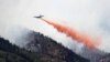 Un avión militar C-130 deja caer sobre las llamas miles de galones de retardador de incendios.