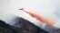 Un avión militar C-130 deja caer sobre las llamas miles de galones de retardador de incendios.